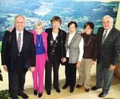 From left, Bernd Dreesman, Margot Heuman, Jutta Dreesman, Joan Fromm, Sharon Goldstein, and Egon Fromm stand in front of a mural of Hellenthal.