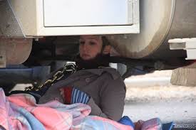 A conservationist lies chained under a log truck in Tasmania. Joanna Pinkiewicz, Code Green. Topics: activism-and-lobbying, forests, bell-bay-7253 - 2815966-3x2-940x627