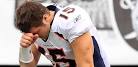 Tim Tebow kneels on the ground