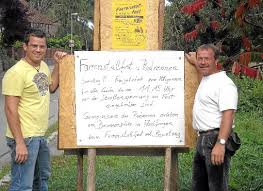 Vorsitzender Alexander Erhart (rechts) weist mit einem kurzfristig erstellten Plakat auf die eingeschränkte Zufahrt zum Farrenstall am Sonntag hin.