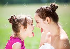 mother daughter tongue|Close-up of cheerful mother and daughter showing tongues to each other in  kitchen stock photo
