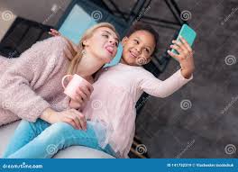 mother daughter tongue|Mother and daughter sticking out tongue while taking selfie in park stock  photo